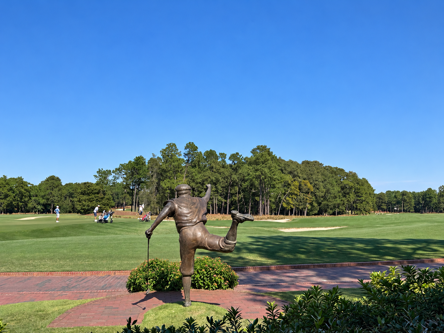 Payne Stewart statue overlooking a Pinehurst fairway and green under a clear blue sky
