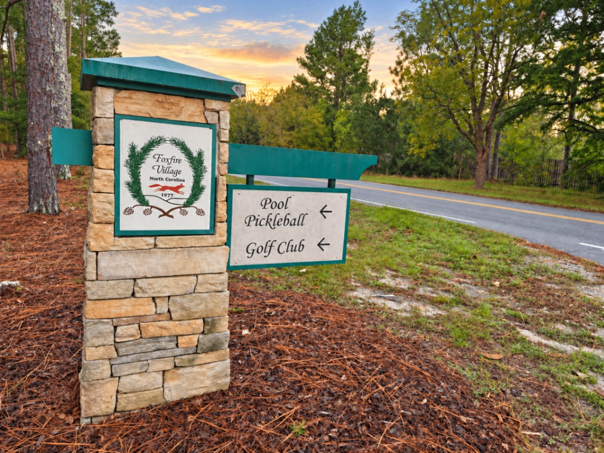 Foxfire Village sign with directions to the pool, pickleball, and golf club at sunset