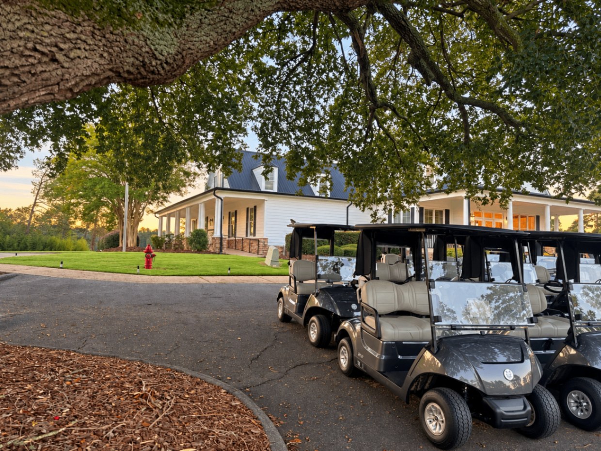 Golf carts lined up beneath an oak limb outside the white Foxfire clubhouse
